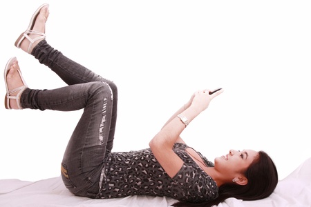 beautiful young girl laying on a pillow chatting on a cell phone の写真素材