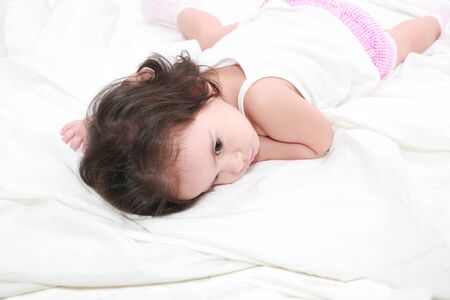 adorable toddler girl on the bed at homeの写真素材