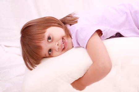 Beautiful little girl lying on bed の写真素材