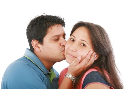 Portrait of woman looking at camera with man near by kissing her の写真素材