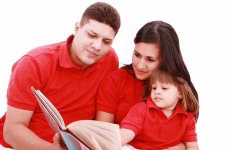 Family sitting on floor reading book at homeの写真素材
