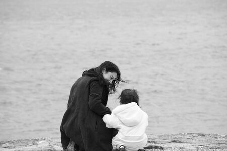 Back view of mother and daughter in beautiful spring seaの写真素材