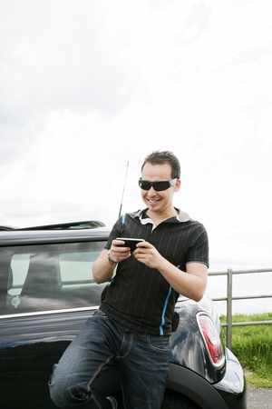 Happy man using his mobile outside his carの写真素材