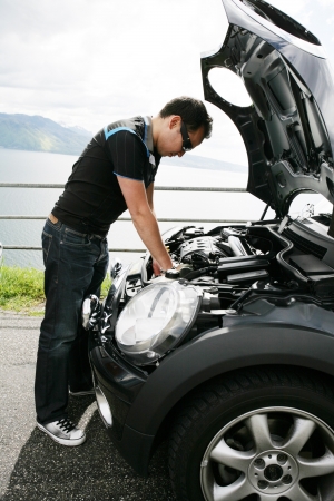 A young man fixing his car up the hillsの写真素材