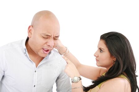 Beautiful Caucasian woman twisting boyfriend's ear while he screams の写真素材