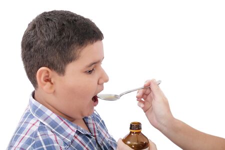 Child taking cough medicine because of the flu の写真素材