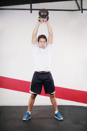 Young man doing kettlebell workout on gymの写真素材