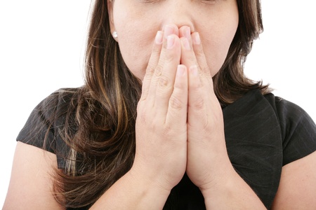A young woman praying with her hands together on white background の写真素材