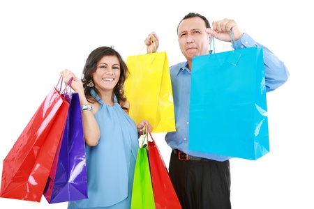 Couple at shopping ,the young woman it is very happy and laughing with bags in her hands while the man it is sad,bored or tired of shopping の写真素材