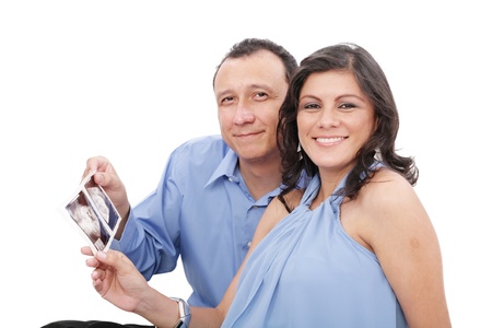 Attractive hispanic young pregnant couple expecting a child holding ultrasoundの写真素材