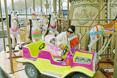 Woman with little child on carouselの写真素材