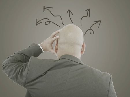 Worried businessman with arrows in different directionsの写真素材