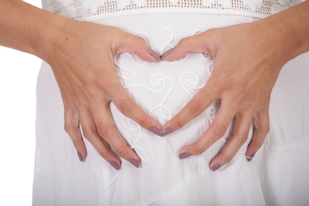 Woman holding her hands in a heart shape on her pregnant bellyの写真素材