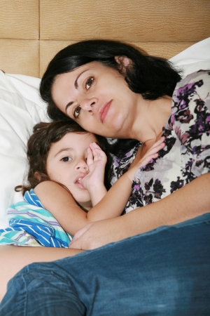 beautiful young mother and her daughter on the bedの写真素材