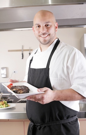 Chef presenting a juicy steak in the kitchenの写真素材