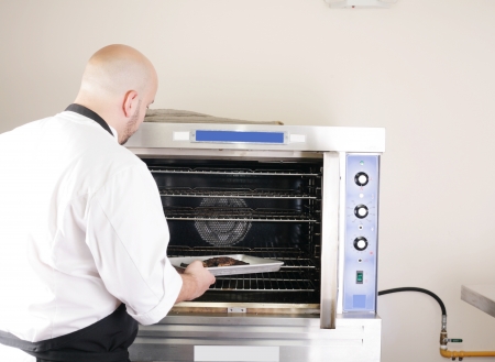 chef putting a tray of a juicy steak in a professional ovenの写真素材
