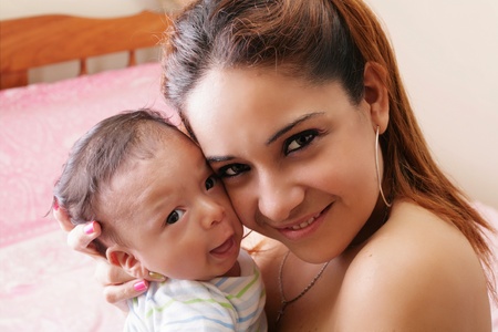 Portrait of a hispanic happy young mother holding a baby の写真素材