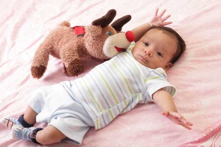 hispanic baby with teddy bear laying on bedの写真素材