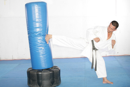 Black belt Karate man practicing in a sandbagの写真素材