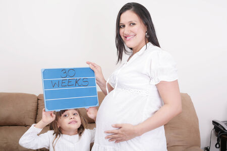 Girl holding a 30 weeks sign to her expectant mother