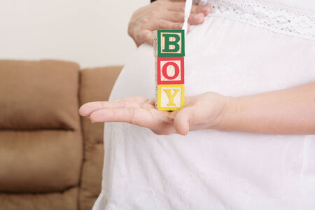 pregnant woman having the word "boy" with wooden blocks written on her handの写真素材
