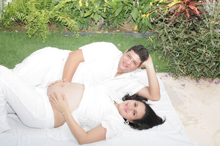 Happy beautiful pregnant woman with his husband outdoorsの写真素材