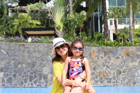 Girl with her mother outside swimming pool enjoying the summerwith their sunglassesの写真素材