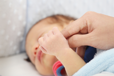 Slept baby hand holding mother finger の写真素材