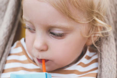Close up little baby girl drinking with strawの写真素材