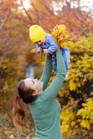 Happy young mother playing with little daughter in autumn parkの写真素材