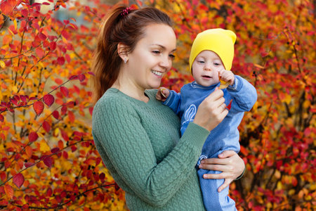 Family in a autumn park. Mother in a green sweater. Cute little girl.の写真素材