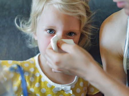 Parent hand helping the little girl to blow her nose with a hygienic wet wipe. Seasonal sickness.の写真素材