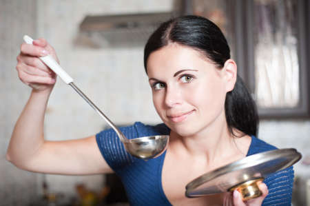 Young housewife cooks food in kitchen. Soup. Dinnerの写真素材