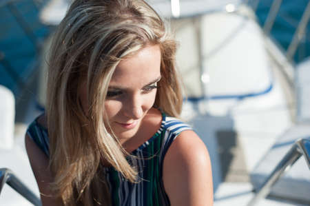 young blonde in a turquoise dress walks on the embankment. sun. summer. restの写真素材