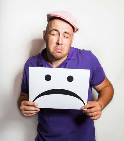 sad young man holds the plate with a sad smile. Emotion. Isolated on whiteの写真素材