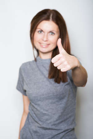 young, beautiful woman shows a thumb. islated on whiteの写真素材