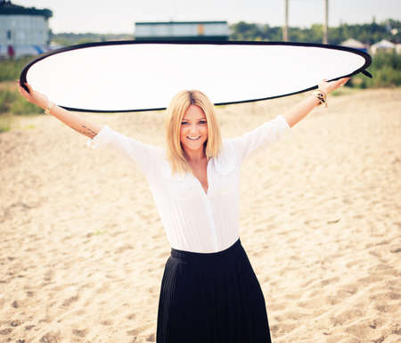 young beautiful woman blonde poses on a beach. dressed in a white shirt and a black skirt. fashion...