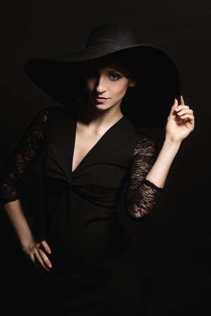 Portrait of a very beautiful girl in black dress and hatの写真素材