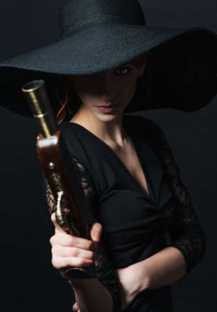 girl pirate with ancient pistol in hand on a black backgroundの写真素材