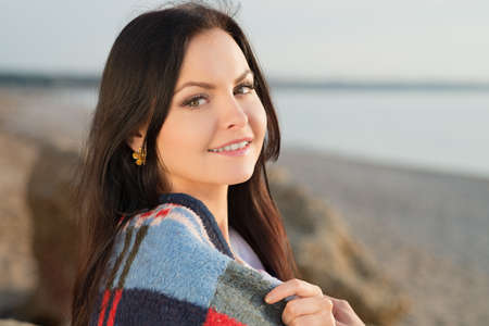 Brunette woman outdoors in check pattern plaid smiling and looking sideways. Copy spaceの写真素材