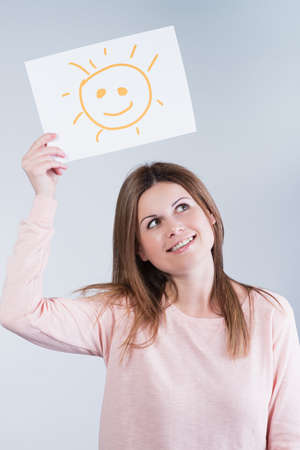 Young woman holding a cardboard with a sunの写真素材