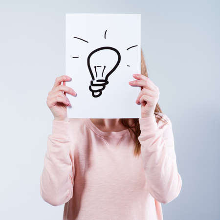 Young woman holding a paper with light bulbs. の写真素材