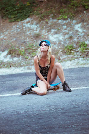 Beautiful young woman sitting over a skateboardの写真素材