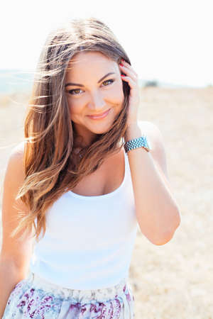 Portrait of the young beautiful smiling woman outdoors enjoying summer sun