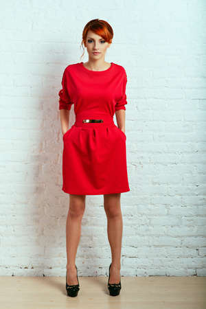 Beautiful young fashionable woman posing in red dress, smiling, looking at camera. Vogue Styleの写真素材