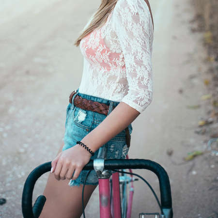 young pretty blonde woman posing  in summer sunshine. hipster. bike.の写真素材