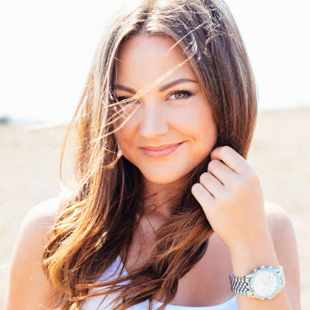 Portrait of the young beautiful smiling woman outdoors enjoying summer sun.