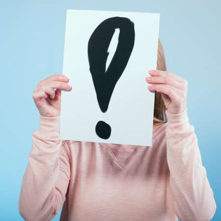 Young woman holding a cardboard with exclamation mark.  の写真素材