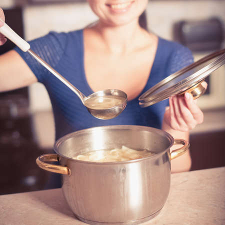 Young housewife cooks food in kitchen. Soup. Dinnerの写真素材