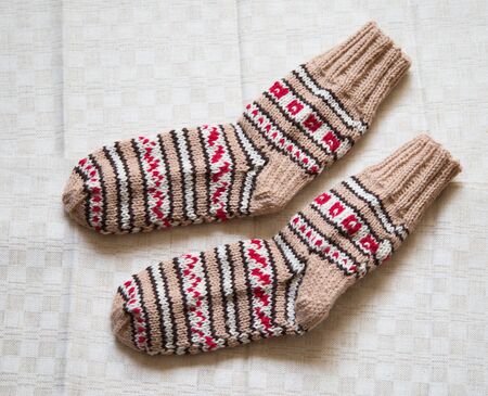 Pair of warm woolen colorful knitted socks on a linen backgroundの写真素材